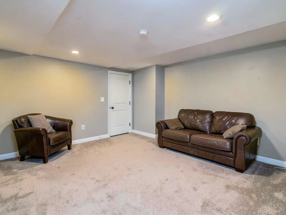The same basement with the walls painted gray, with the door, baseboards, furniture and ceiling kept