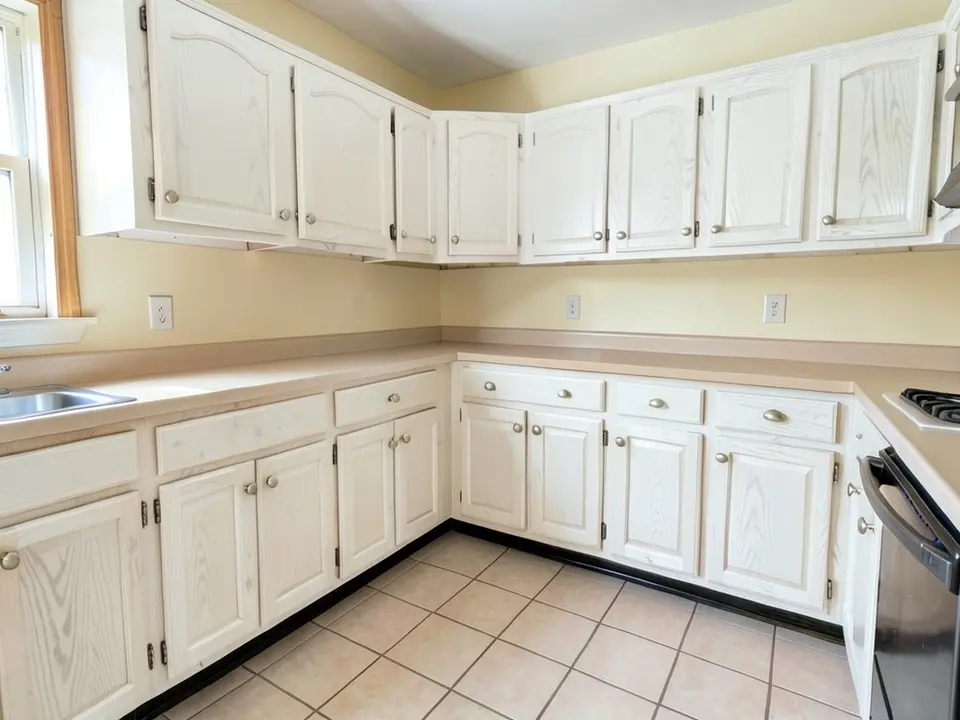 The same kitchen with the oak cabinets painted white with the wood grain still showing through
