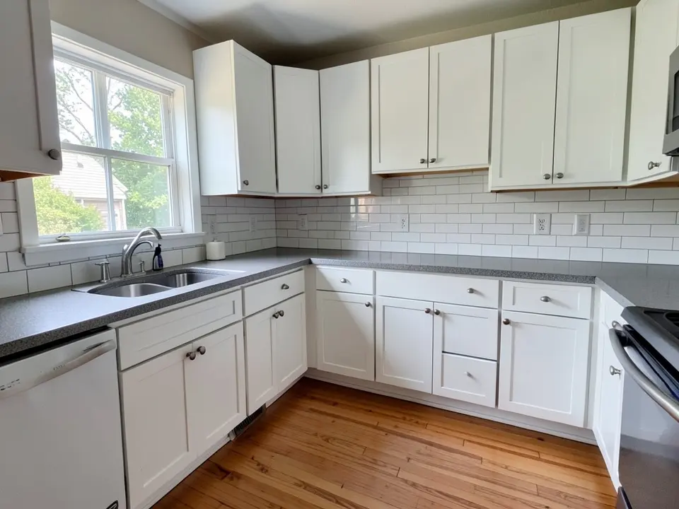 Kitchen with white shaker cabinets, gray countertop, white subway tile backsplash and a wood floor, before