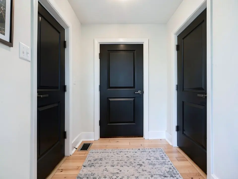 The same hallway with the three paneled doors painted black, with the white walls and white casings kept