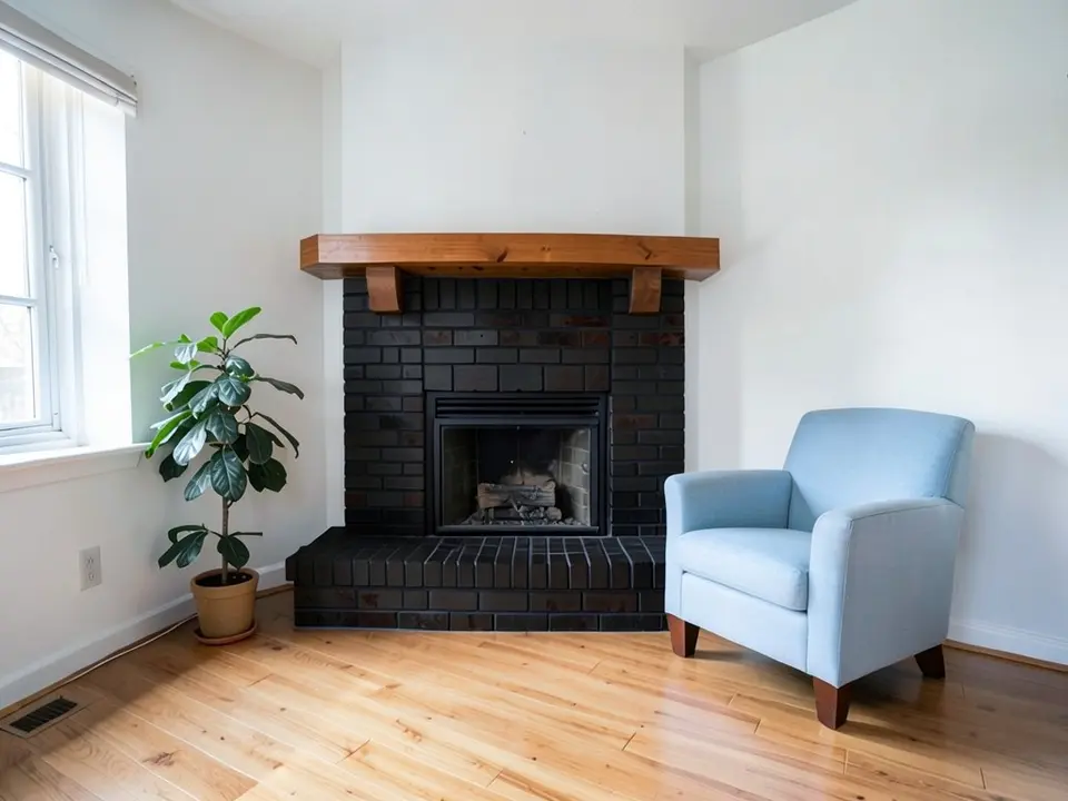 The same room with the brick fireplace and hearth painted black, with the wooden mantel kept