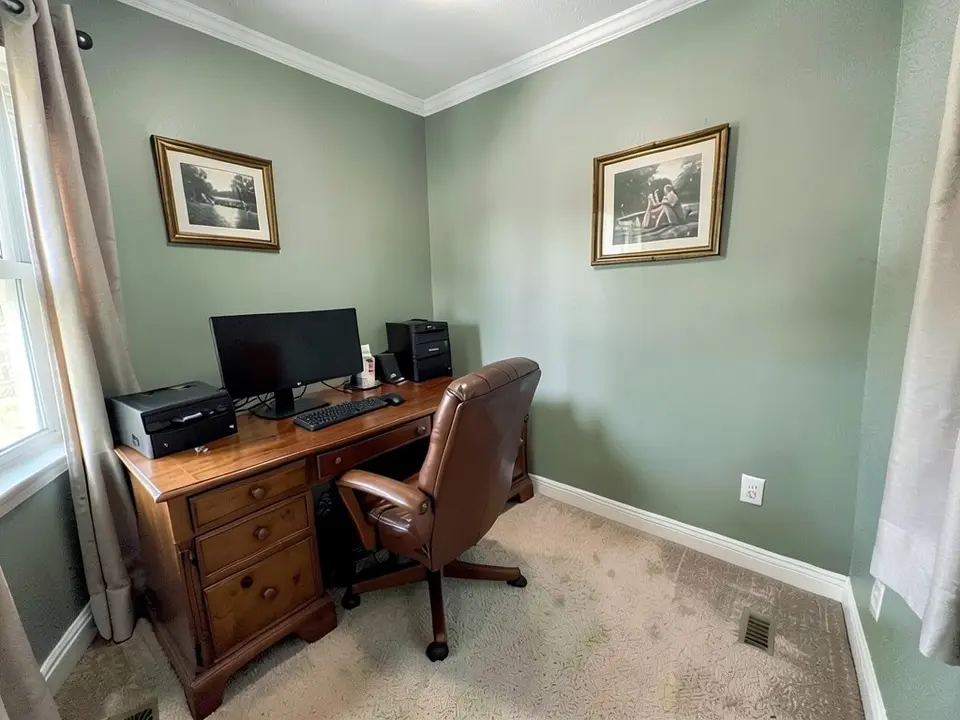 The same home office with the walls painted gray-green, with the molding, curtains and pictures kept and the monitor, chair and carpet redrawn