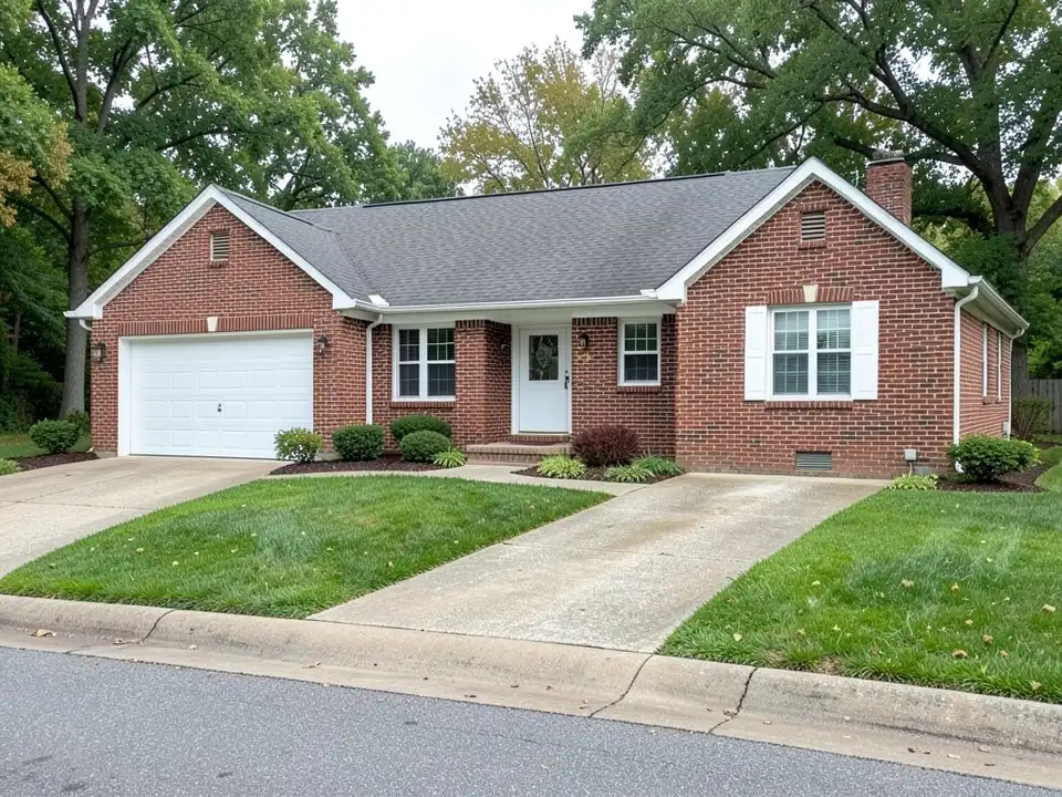 Single-story red brick ranch house with a white garage door, before painting